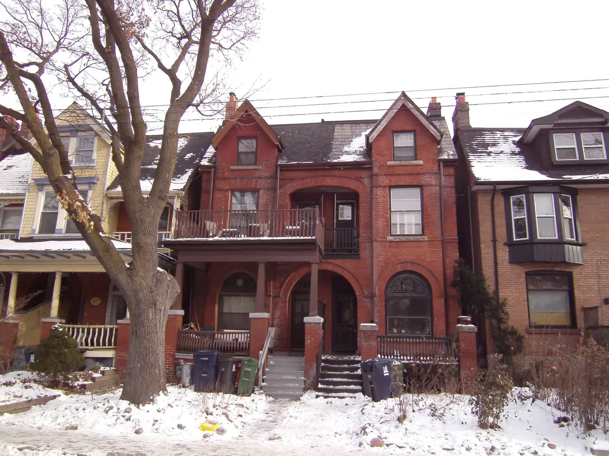 Red-brick semi-detached houses with arched porches on a snowy street in The Annex.