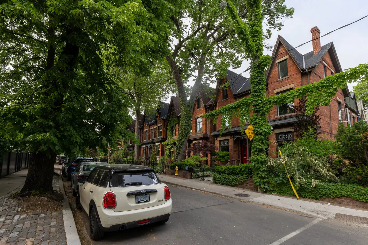 Red-brick Victorian row houses with steep gables and bay windows on a tree-lined Cabbagetown street